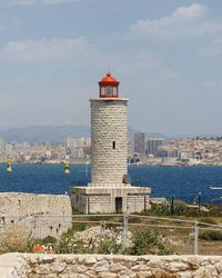 Lighthouse by sea against sky