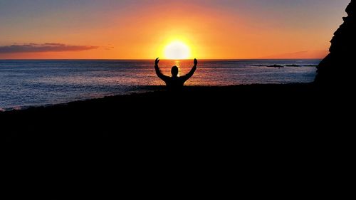 Silhouette man on beach against sky during sunset