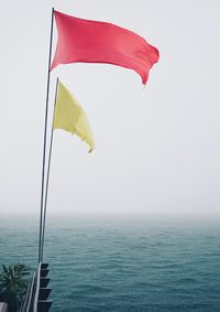 Scenic view of flag on sea against clear sky