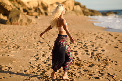 Young woman with arms outstretched standing at beach