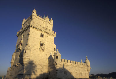 Low angle view of torre de belem against clear blue sky in city