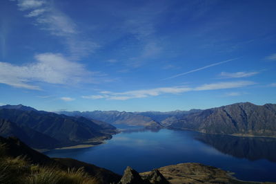 Scenic view of lake and mountains against blue sky