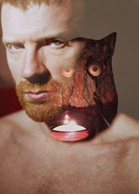 Portrait of shirtless man reflecting on glass against tea light candle