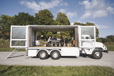 Multi-ethnic business colleagues discussing in portable office truck at park