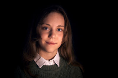 Portrait of smiling girl against black background