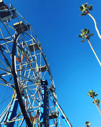 Low angle view of ferris wheel against clear blue sky