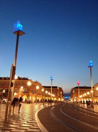 Illuminated street light against blue sky at night