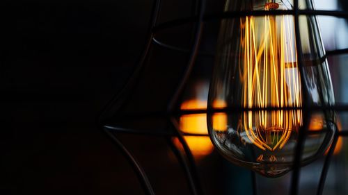 Close-up of illuminated light bulb against black background