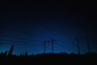 Low angle view of silhouette power line against sky at night