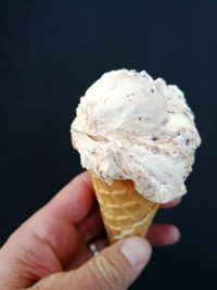 Hand holding ice cream cone against black background