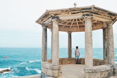 Rear view of man looking at sea against sky