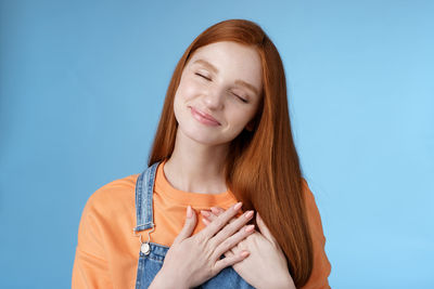 Smiling woman with eyes closed against blue background