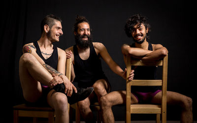 Happy friend sitting on chair against black background