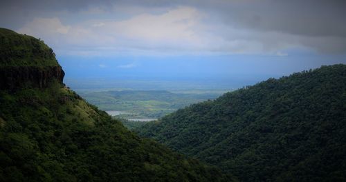 High angle view of lush green landscape against cloudy sky