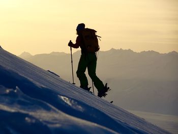 Full length of man on snowcapped mountain against sky during sunset