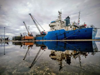 Ship moored in water against sky