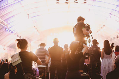 Rear view of people photographing at concert hall