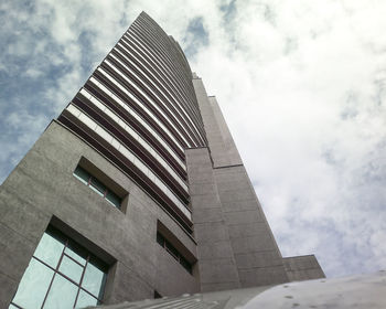 Low angle view of modern building against cloudy sky