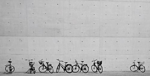 Bicycles parked on sidewalk against wall in city