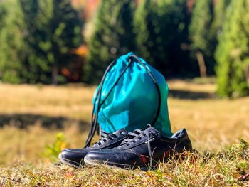 Hiking boots and blue backpack with forest in the background on a sunny day