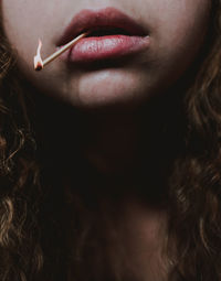 Close-up of woman with matchstick in mouth