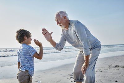 Grandfather and grandson high fiving on the beach