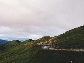 Scenic view of road by mountains against sky