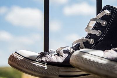 Close-up of shoes on window against sky