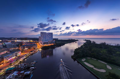 High angle view of illuminated buildings by sea against sky at sunset