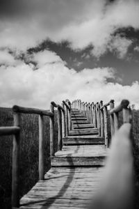 Surface level of wooden footbridge against sky