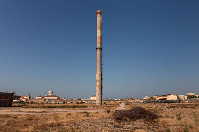 Built structure on field against clear blue sky