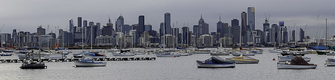 Sailboats moored on harbor against buildings in city