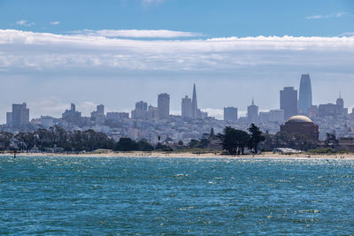 City at waterfront against cloudy sky