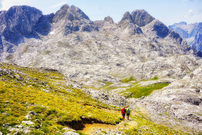 Rear view of hikers walking on mountain against sky