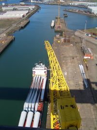 High angle view of crane over ship in river at harbor on sunny day
