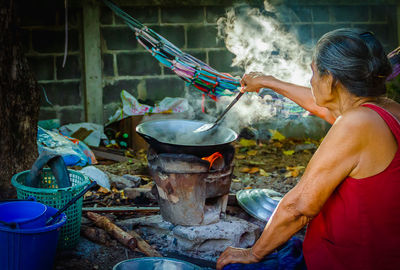 Midsection of woman preparing food on barbecue grill