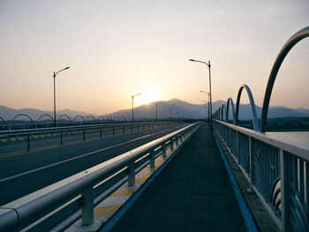 Bridge over road against sky during sunset