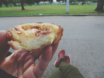 Cropped hand of man holding pastel de nata at jardim da torre de belem