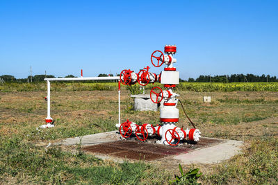 Red valves on grassy field against clear blue sky