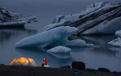 Woman using her laptop at campsite by glacier lagoon