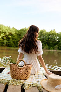 Rear view of young woman sitting by lake