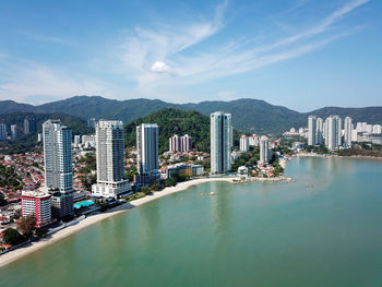 Scenic view of city by bay against sky