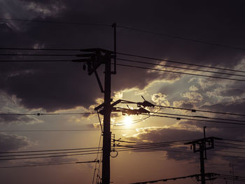 Low angle view of electricity pylon against sky during sunset