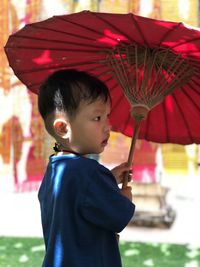 Side view of boy holding umbrella