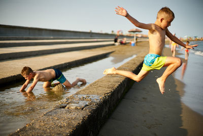 Full length of shirtless boy enjoying in water