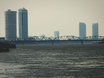 View of suspension bridge in city against clear sky