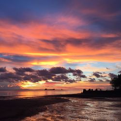 Scenic view of sea against dramatic sky during sunset