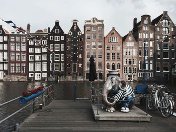 Elephant statue on pier over canal with buildings in background