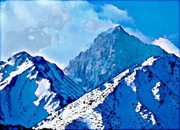 Scenic view of snowcapped mountains against blue sky