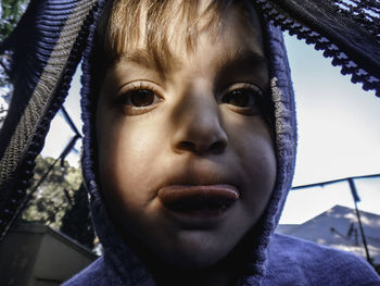 Close up portrait of toddler wearing a hoodie, with runny nose, tongue out